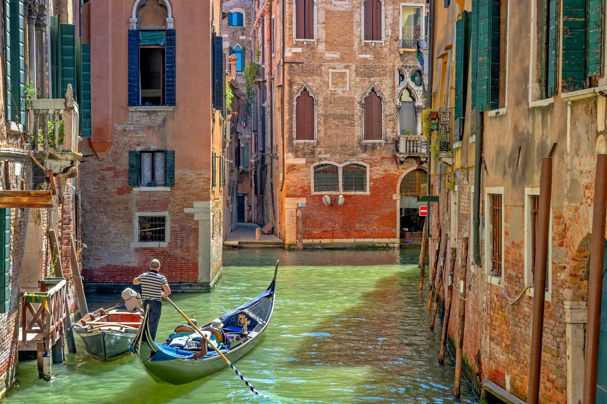 A gondolier steering a gondola through a canal